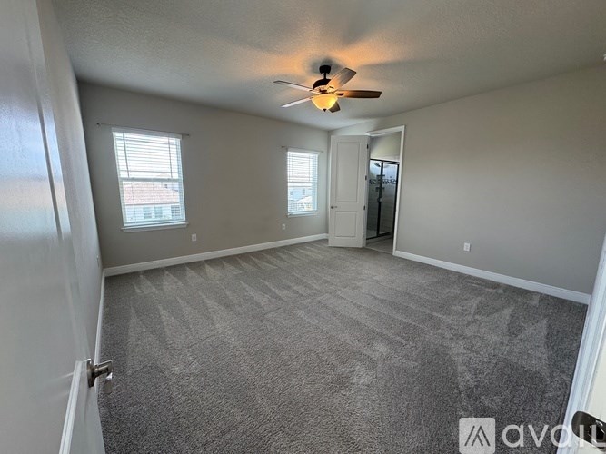 A room with a carpeted floor and a ceiling fan.