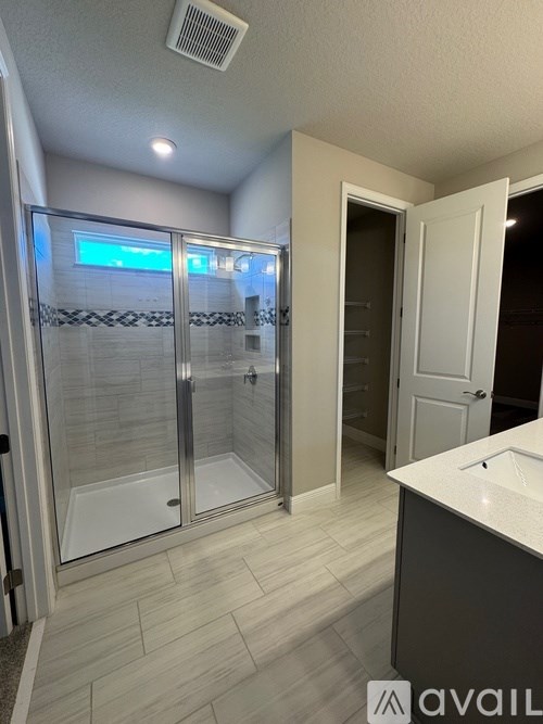 A bathroom with a glass shower door and a white door.