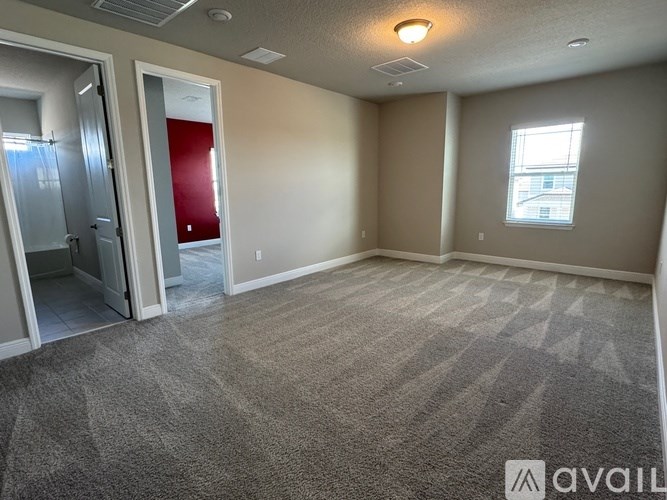 A carpeted room with a doorway leading to another room.