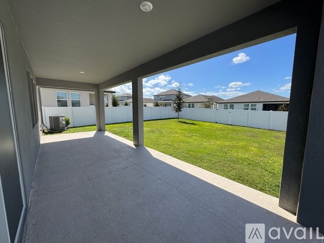 A patio area with a view of a fenceed yard and houses.