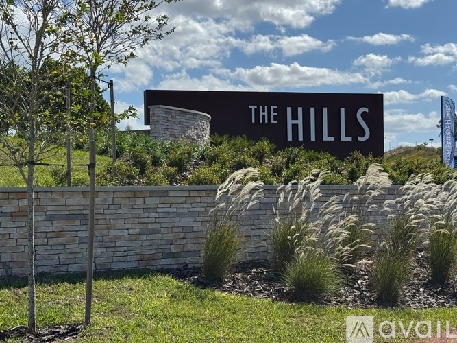 A sign that says "The Hills" is displayed in front of a stone wall.