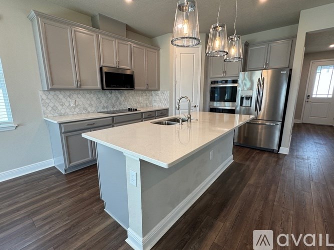 A kitchen with a large island in the middle and wooden floors.