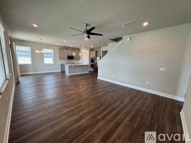 A spacious room with wooden flooring and a ceiling fan.