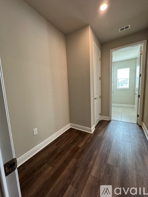A hallway with wood flooring and white walls.
