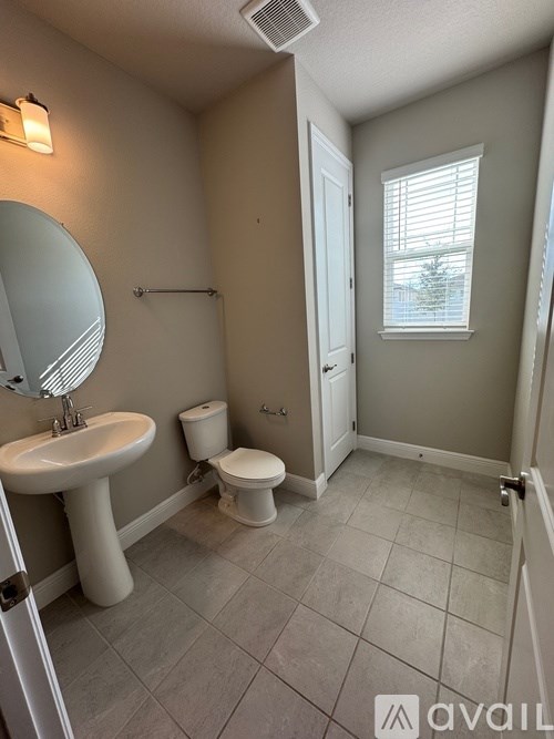 A bathroom with a sink, toilet and a window.