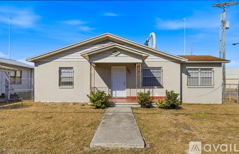 A single-story house with a front porch and a fence in the background.