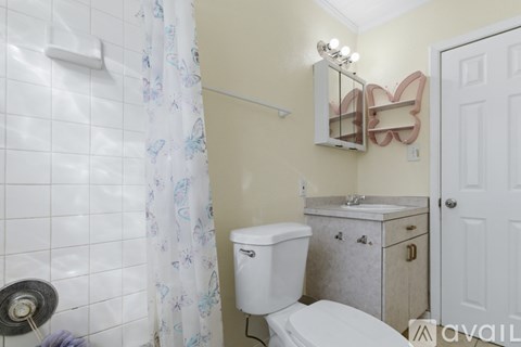 A bathroom with a toilet, sink, and shower curtain.
