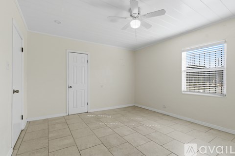 A room with a ceiling fan and a window with blinds.