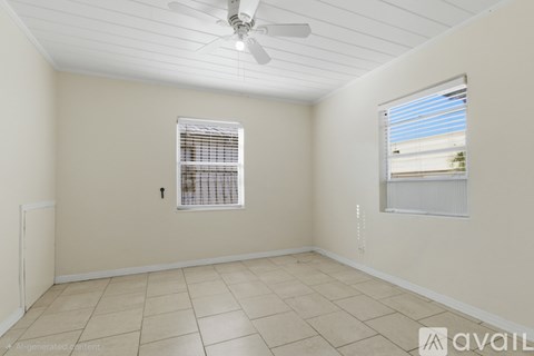 A room with a ceiling fan and two windows.