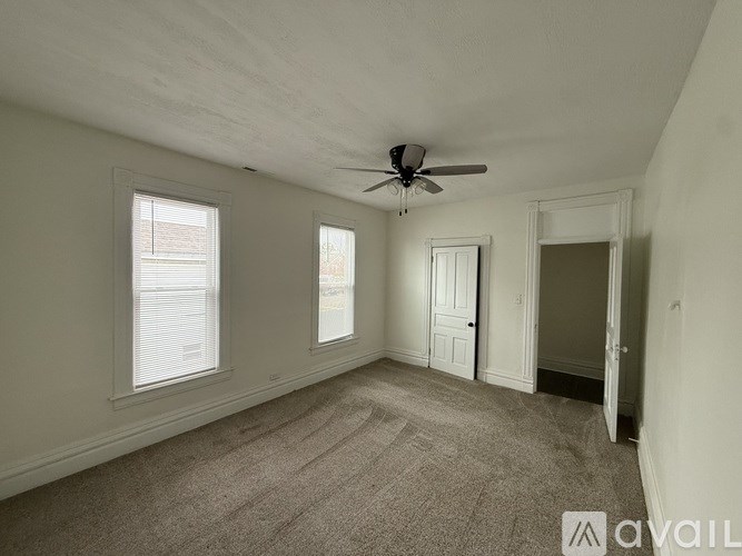 A room with a ceiling fan and carpeted floor.