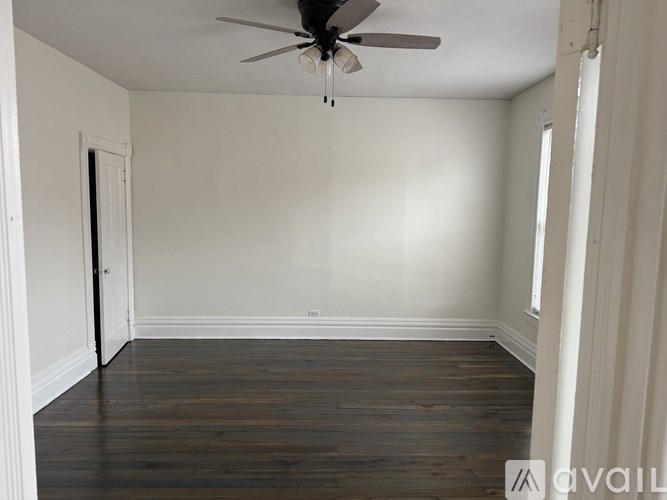 A room with a ceiling fan and wooden flooring.