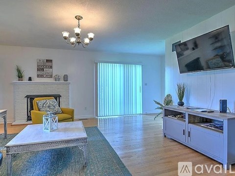 A living room with a yellow chair and a white fireplace.