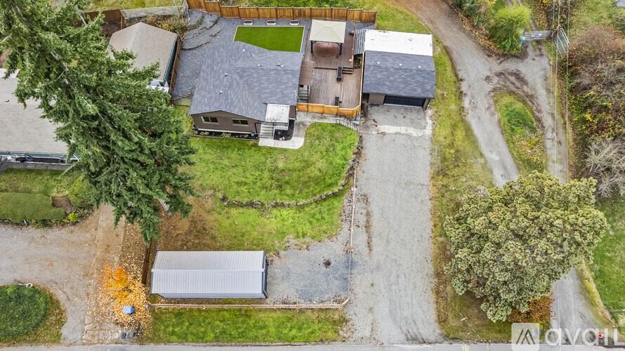 A house with a driveway and a garage is surrounded by trees and grass.