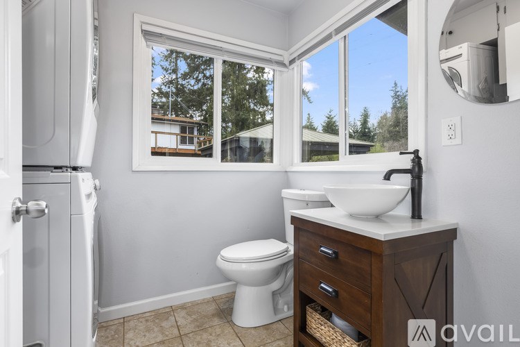 A bathroom with a toilet, sink, and a window.