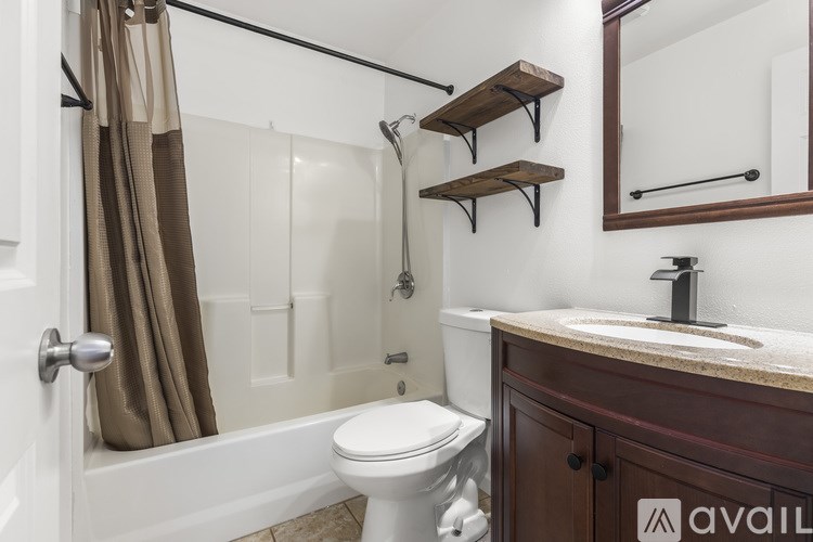 A bathroom with a toilet, sink, and a bathtub with a shower curtain.