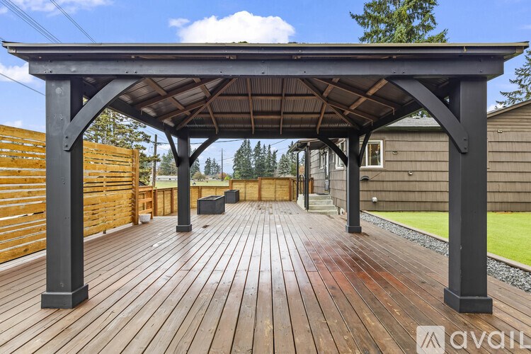 A wooden deck with a pergola and a fence in the background.