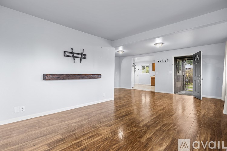 A spacious room with wooden flooring and white walls.