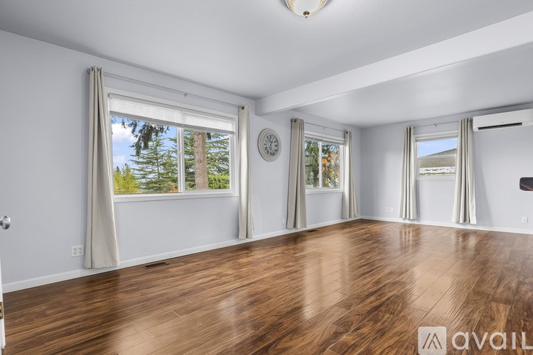A room with wooden floors and a large window with curtains.