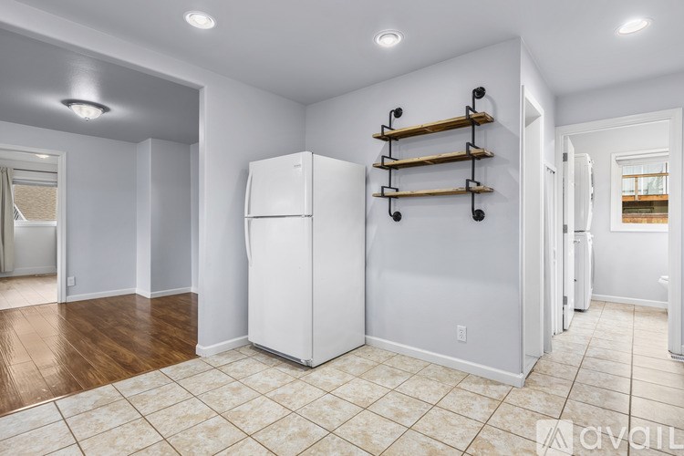 A white refrigerator in a kitchen with wooden shelves above it.