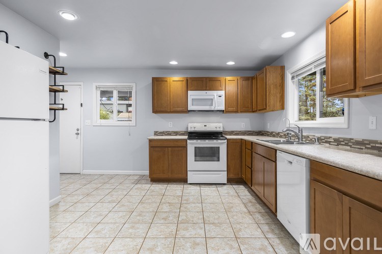 A kitchen with white appliances and brown cabinets.