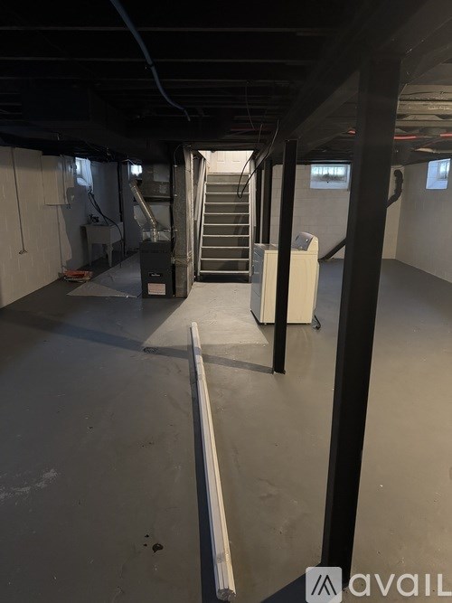 A long hallway with a staircase and a white wall on the right.