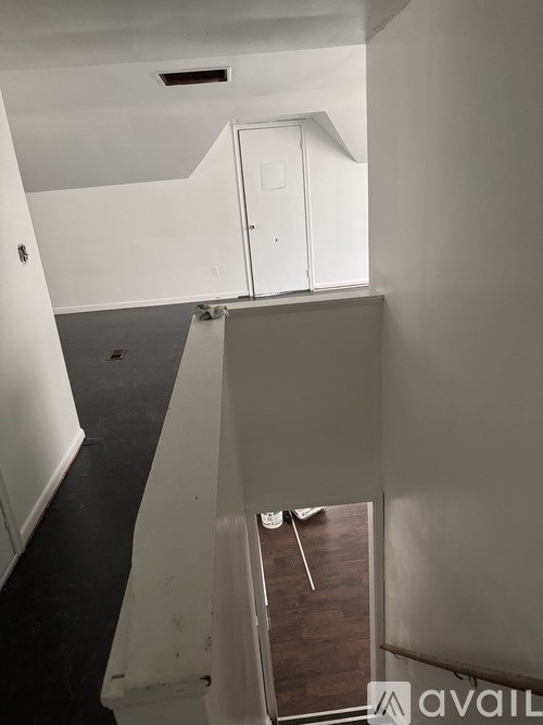 A room with a white door and a wooden floor.