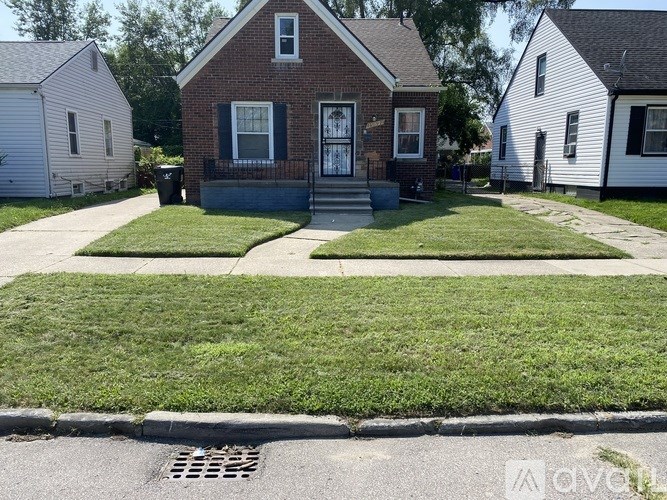 A small brick house with a front porch and a green lawn.