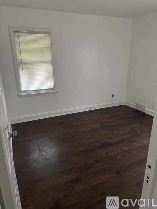 A room with wooden flooring and a window with blinds.