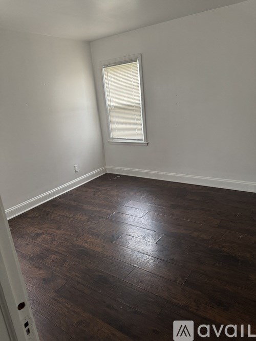 A room with wooden flooring and a window with blinds.