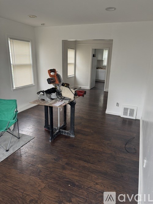 A room with a wood floor and a table with a green chair.