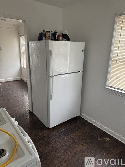 A white fridge in a room with wooden flooring.