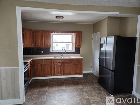 A kitchen with wooden cabinets and a black refrigerator.