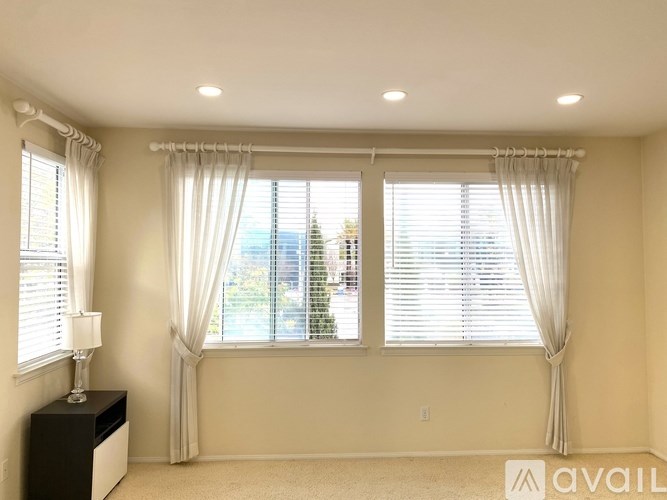 A room with two windows covered by white curtains.