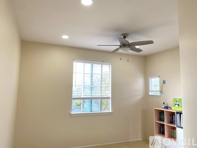 A room with a ceiling fan and a window with blinds.