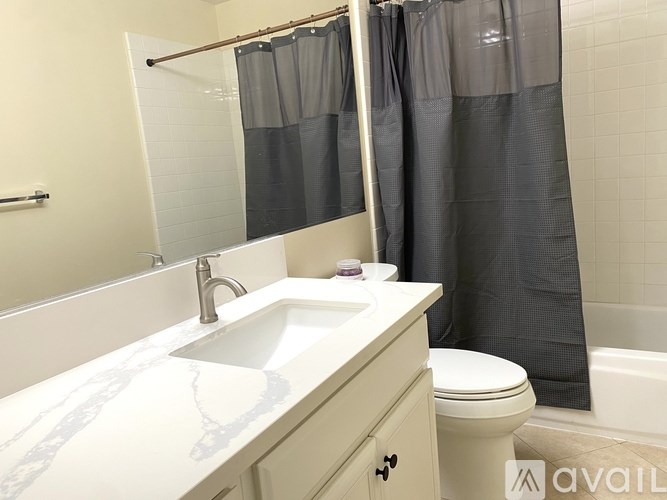 A bathroom with a sink, toilet, and shower curtain.