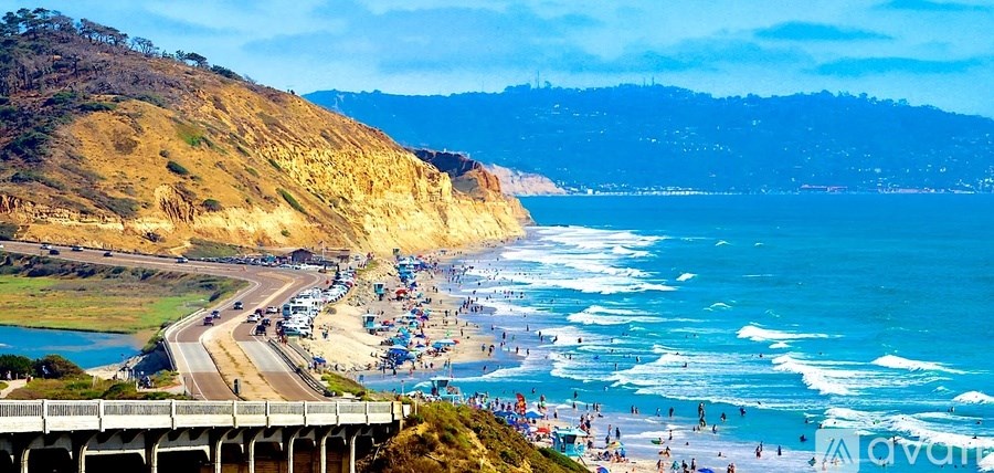 A beach with a pier and a mountain in the background.