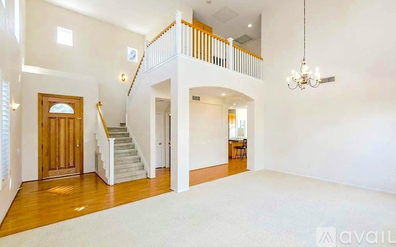 A large, empty room with a staircase and a chandelier.