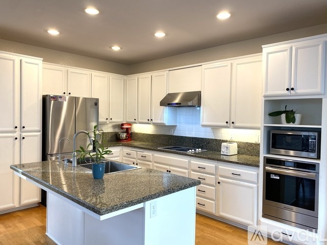 A kitchen with a granite countertop and stainless steel appliances.