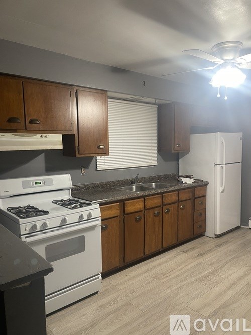 A kitchen with a white stove and wooden cabinets.