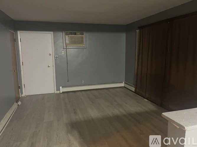 A room with a white door and a window with a curtain.