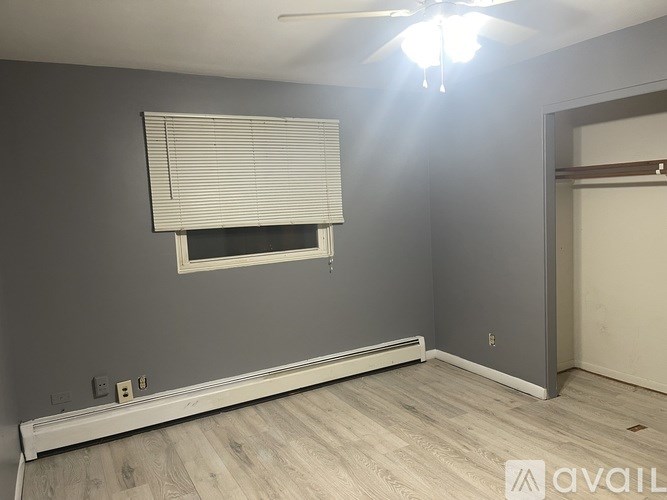 A room with a window covered by blinds and a ceiling fan.