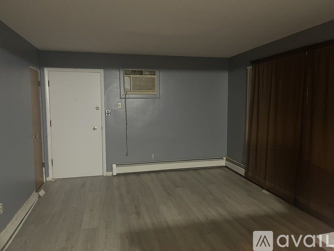 A room with a white door and a window with a white air conditioner unit.