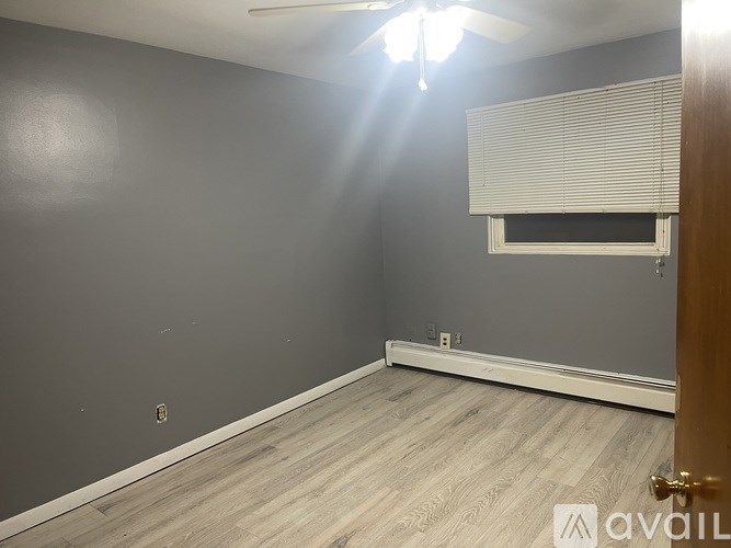 A room with a ceiling fan and a window with blinds.