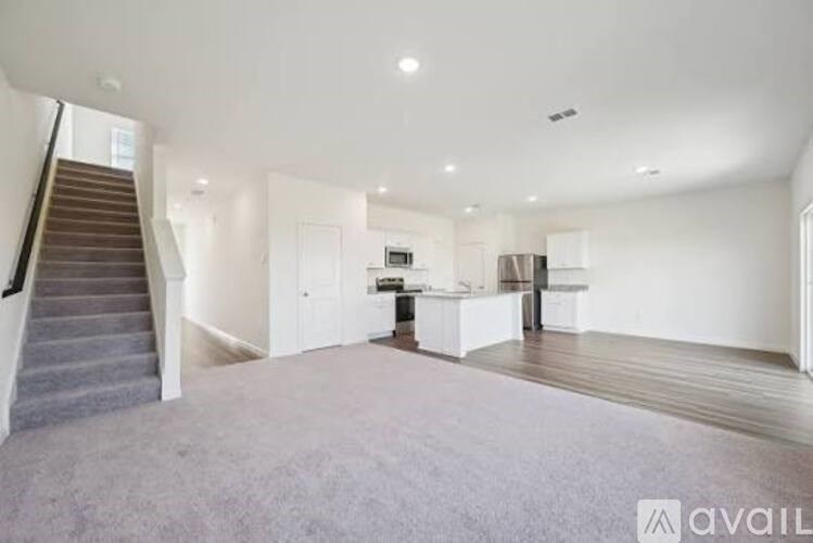 A spacious living room with a staircase on the left side.