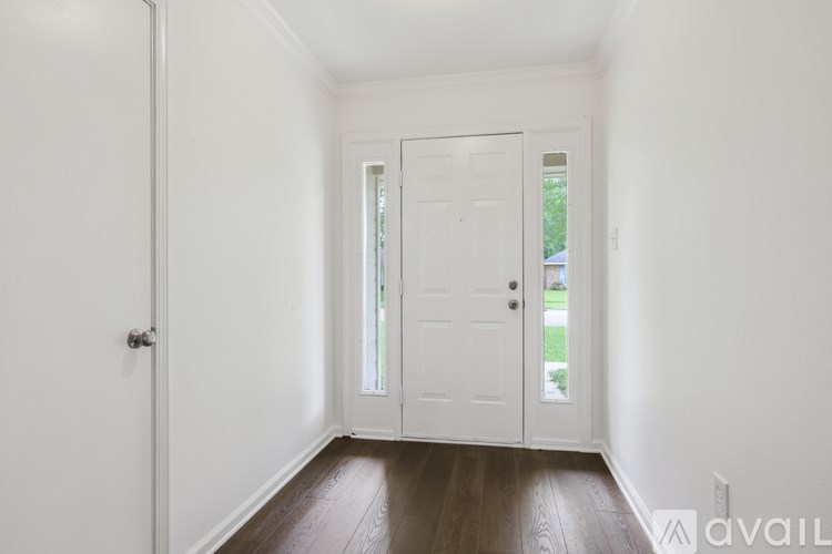 A white door with a glass window is in a room with white walls and wooden floors.