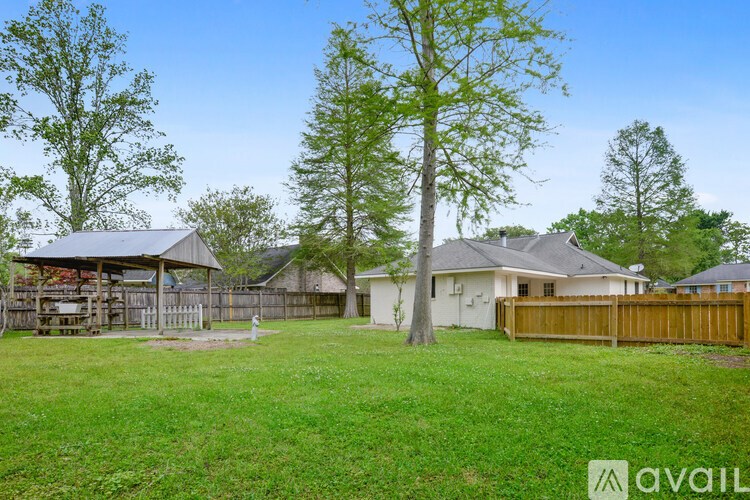 A grassy yard with a house and a tree in the background.