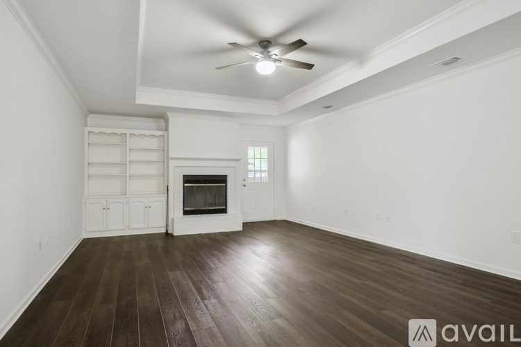 A spacious room with a wood floor and a ceiling fan.