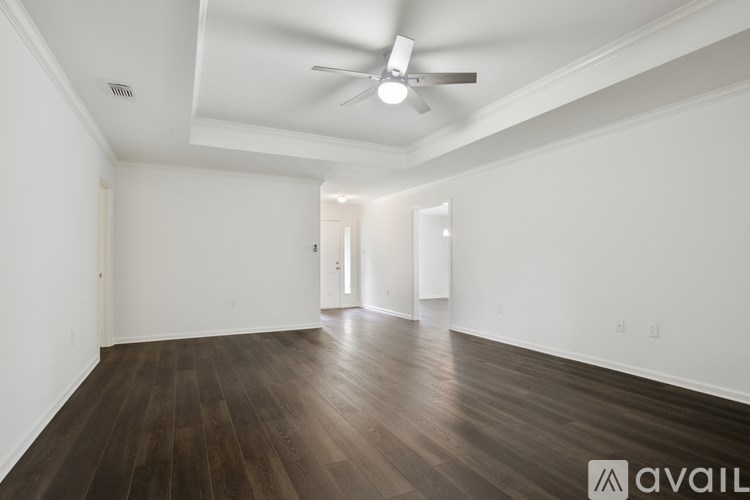 A spacious room with wooden floors and a ceiling fan.