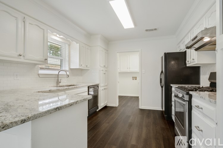 A kitchen with white cabinets and a black refrigerator.