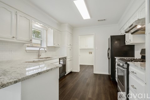 A kitchen with white cabinets and a black refrigerator.